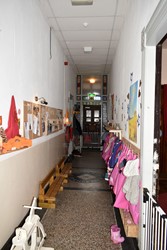 <p>De brede middengang met terrazzo vloer en hardstenen plint. Achterin het tochtportaal met glas-in-lood.</p>
